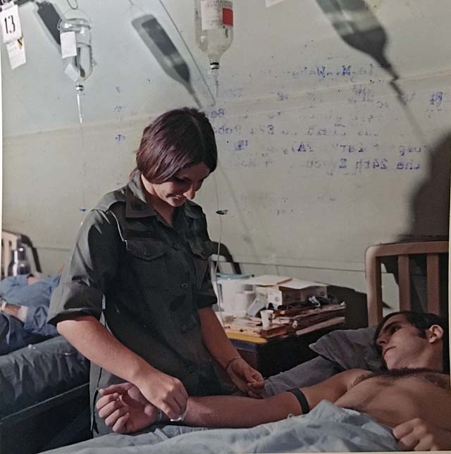 1st Lt. Kathie M. Weber administers intravenous fluid to Spec.4 Robert J. Vanaman of Co. D, 1st Bn., 7th Cav Regt., at the 24th Evac Hospital in Long Binh, July 1971.