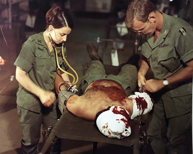 Capt. Bernice Scott and Lt. David Van Voohels cut the field bandages off a newly received patient at the 2nd Surgical Hospital in Chu Lai, September 1969.